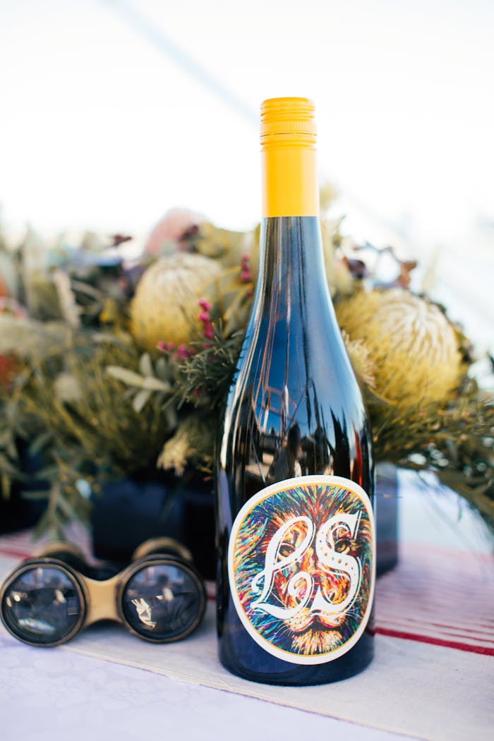 A stylish wine bottle with floral decor and binoculars on a table, ideal for celebrations.