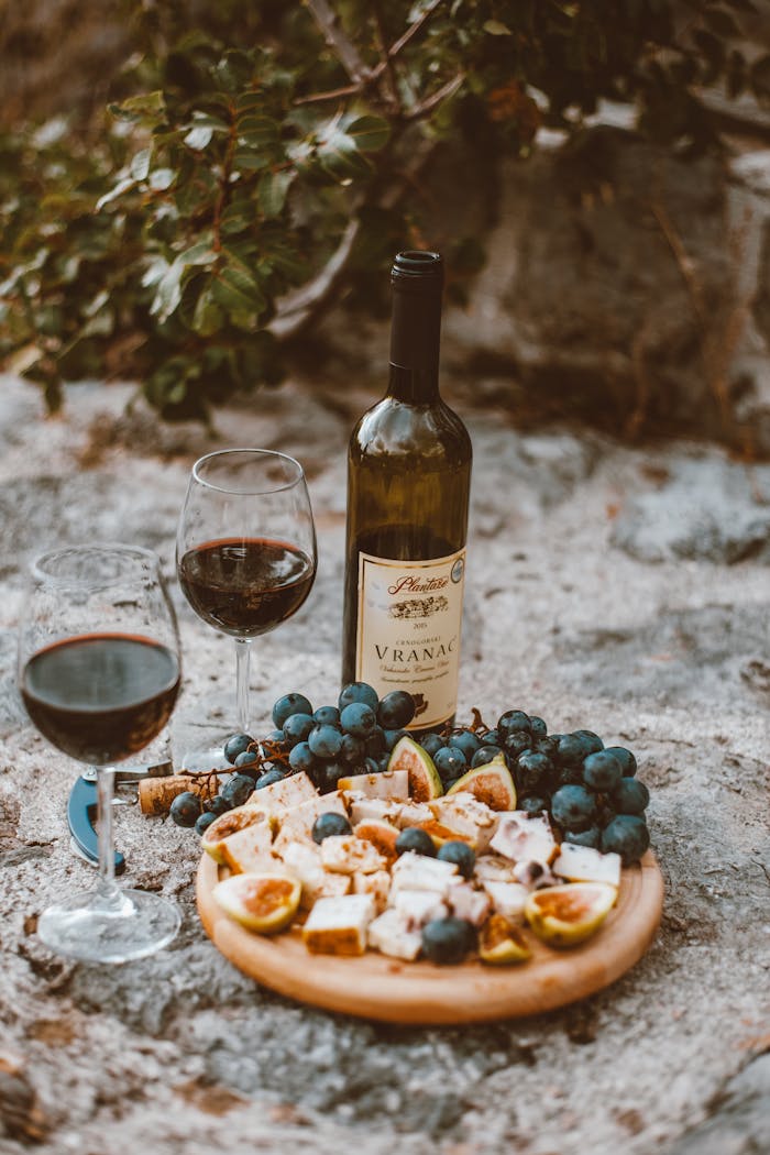 Home A rustic outdoor wine and cheese platter with grapes and figs, perfect for a cozy picnic.